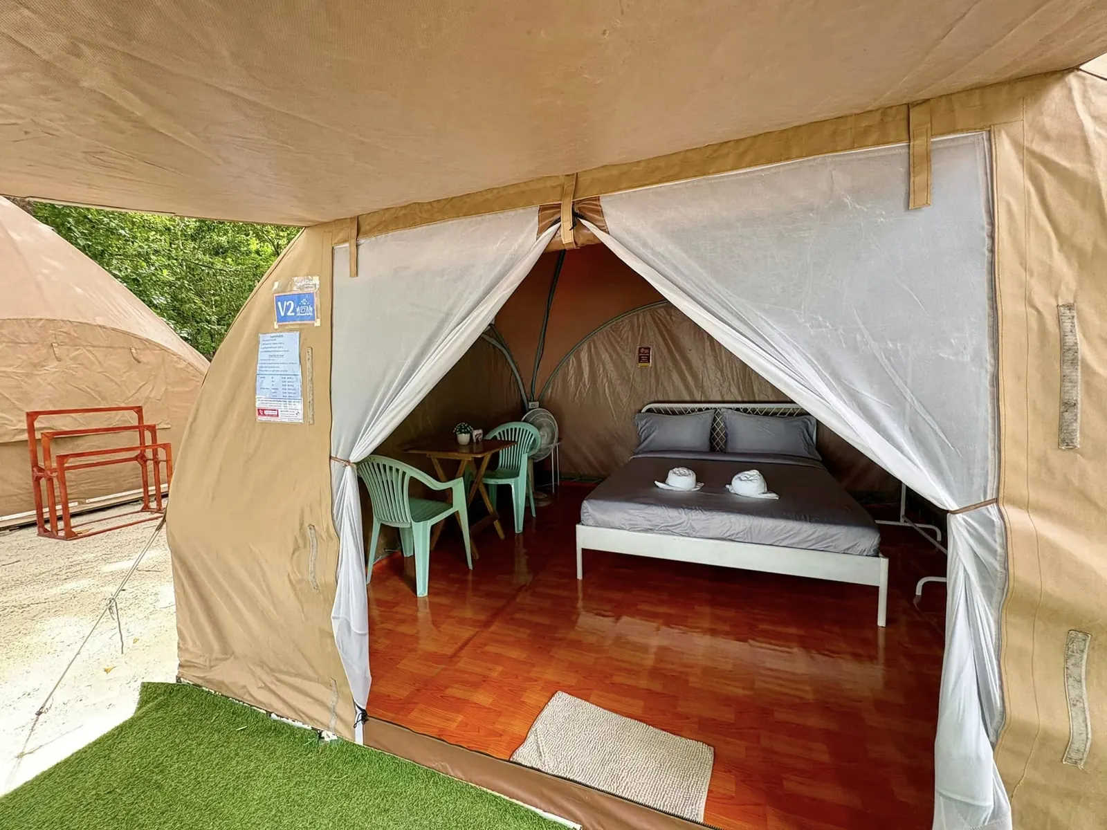 Air-conditioned tent interior with double bed and simple furniture