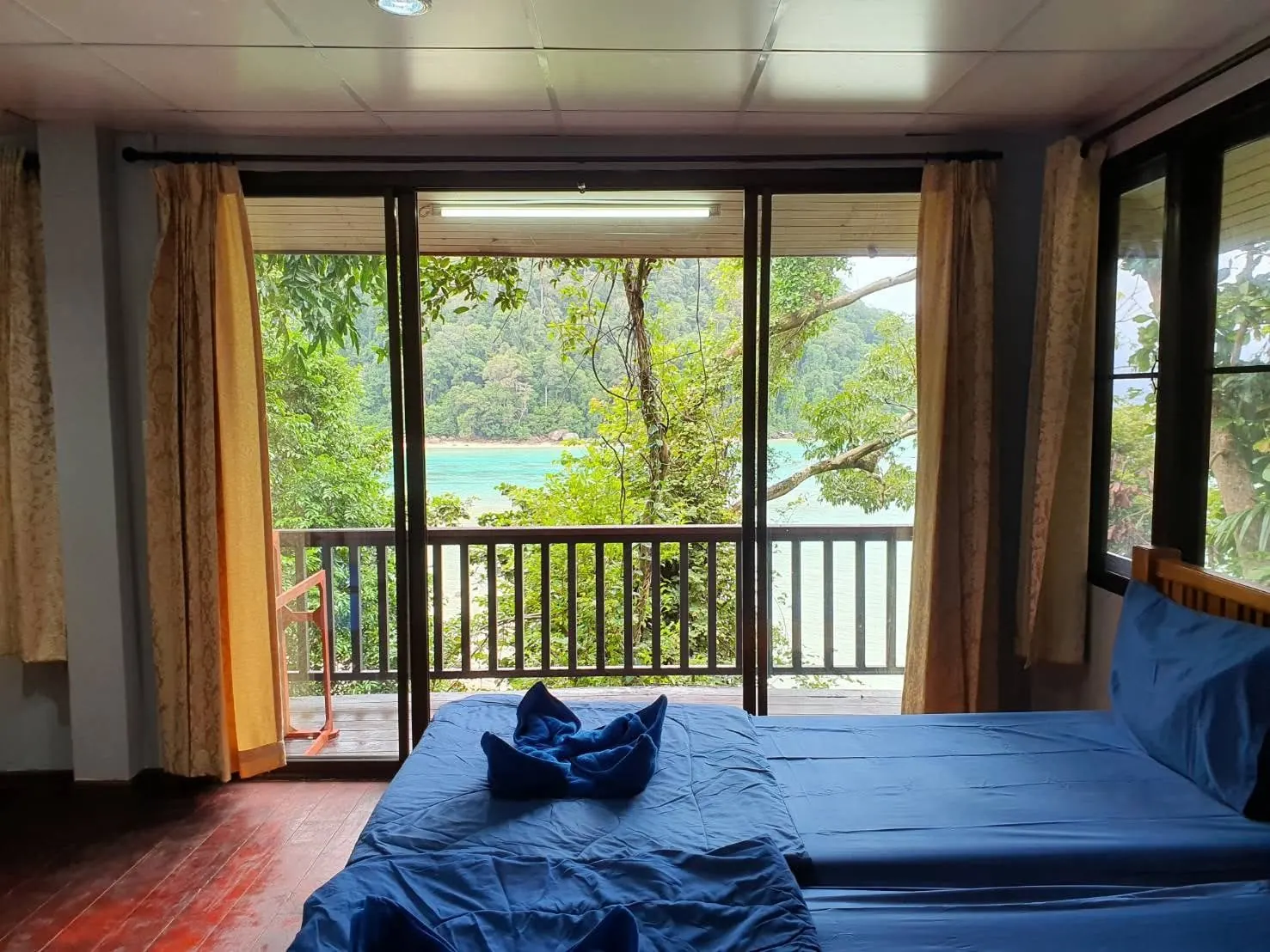 Beds inside a two-person bungalow with turquoise sea visible beyond the windows